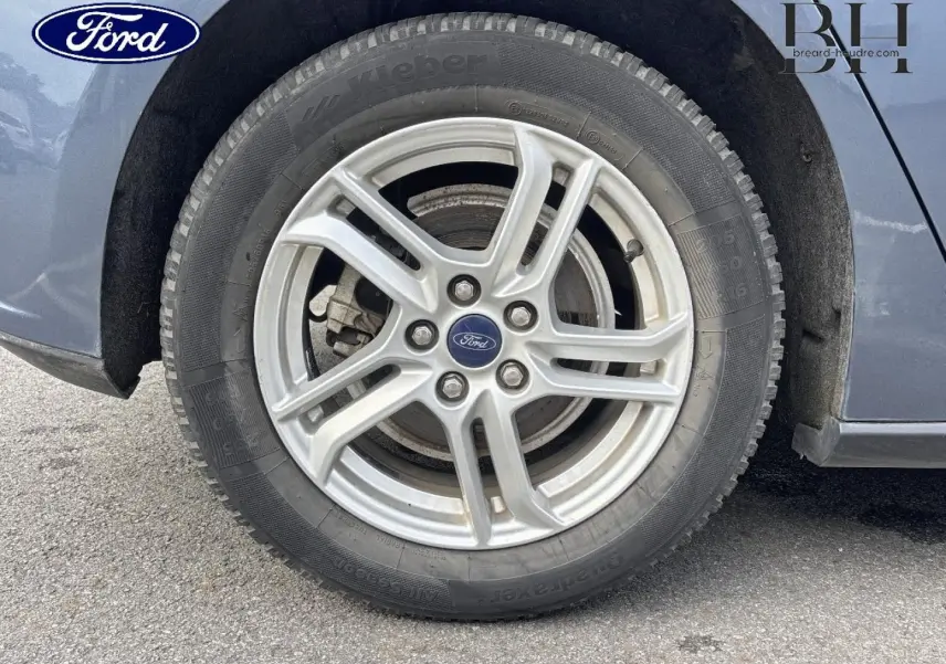 Gros plan sur la roue avant droite avec jante alu argentée d'une Ford Focus bleu azur métallisé.