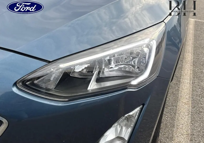 Gros plan sur le phare avant droit d’une Ford Focus 1.5 EcoBlue bleu azur métallisé avec détails du capot et pare-chocs.