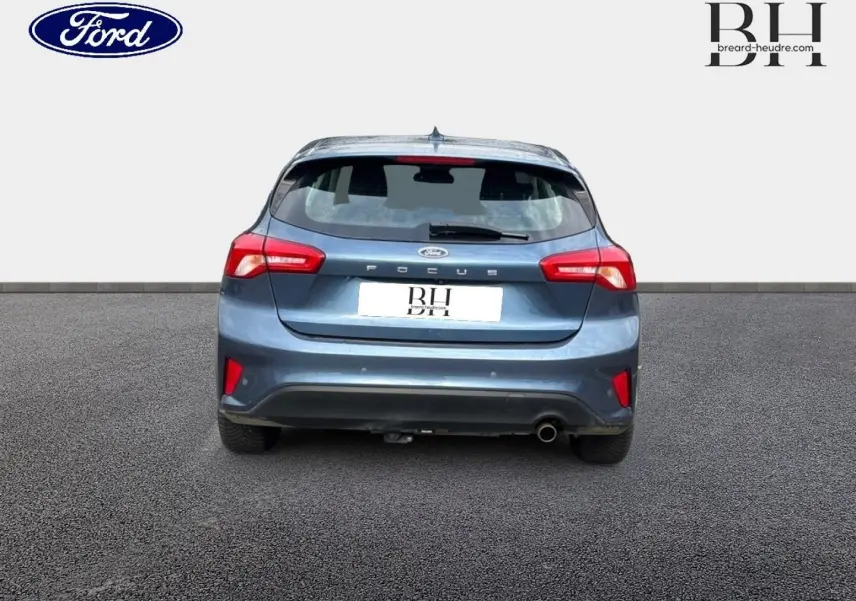 Vue arrière d'une Ford Focus bleu azur métallisé de 2020, avec feux rouges et sortie d'échappement chromée visible.