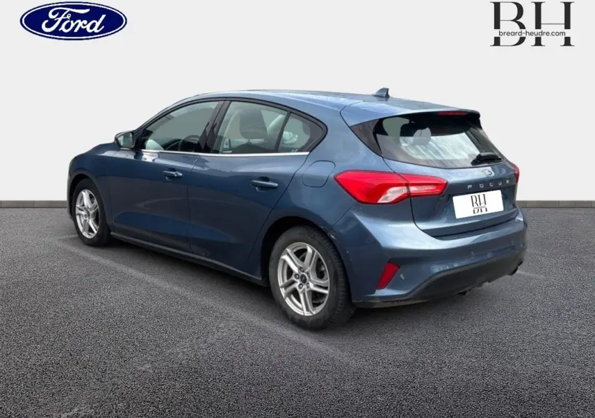 Ford Focus 1.5 EcoBlue bleu azur métallisé vue 3/4 arrière côté gauche, jantes alu et feux arrière LED visibles.