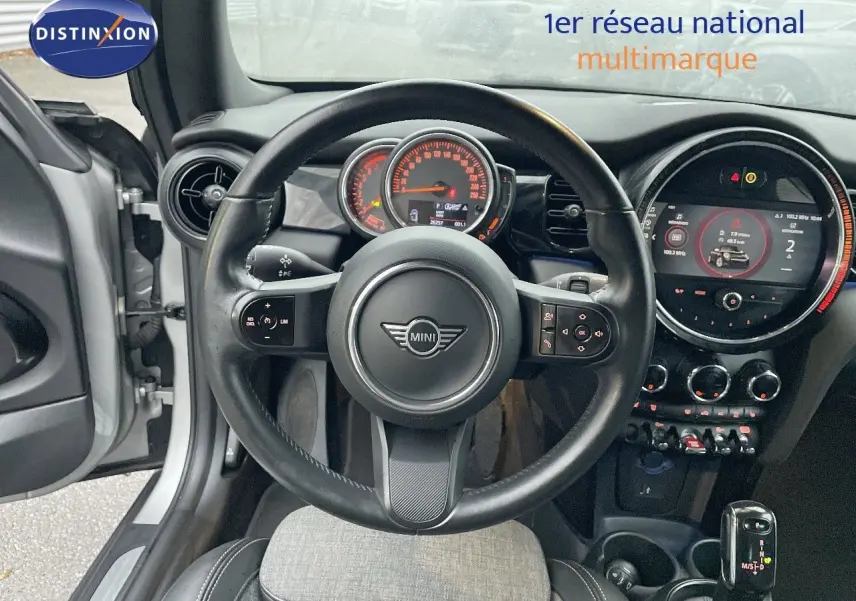 Vue intérieure centrée sur le volant et le tableau de bord d'une MINI Cabriolet Melting Silver 2023, détails modernes visibles.