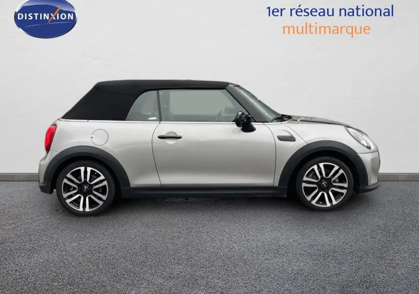 Profil droit d'une MINI Cabriolet 2023 couleur argent métallisé avec toit noir fermé sur fond neutre.
