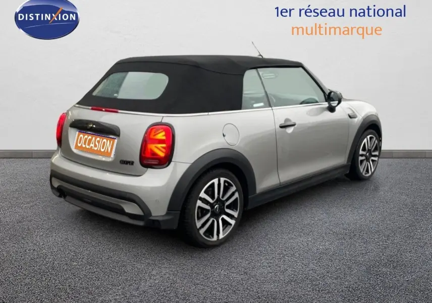 Vue 3/4 arrière droite d'une MINI Cabriolet 2023 Melting Silver avec toit noir et feux arrière à motif Union Jack.