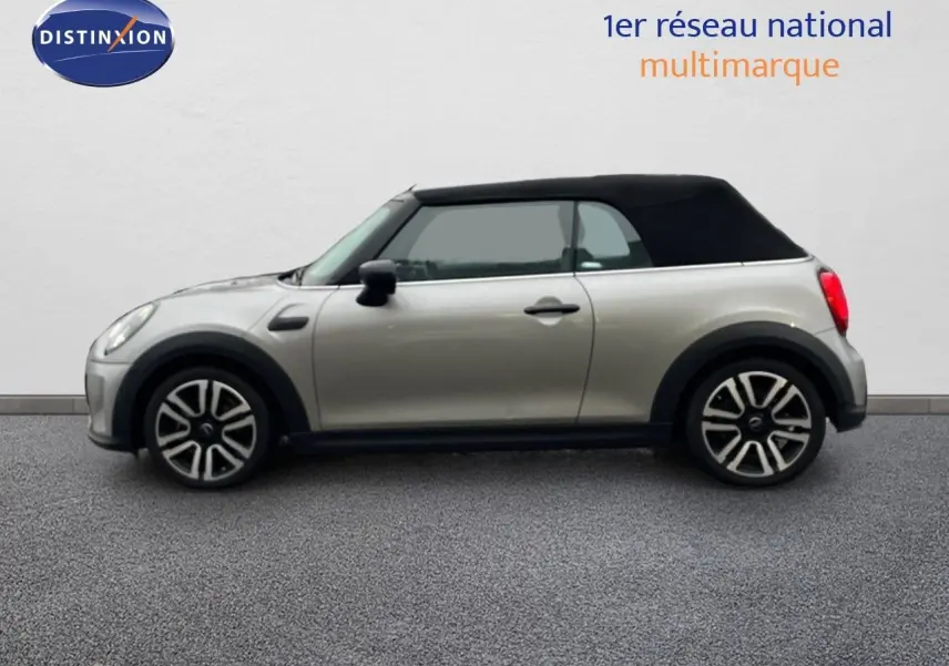 Profil gauche d'une MINI Cabriolet 2023 couleur Melting Silver avec capote noire fermée sur fond neutre.