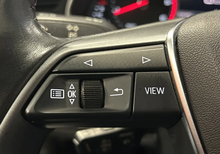 Gros plan sur les commandes gauche du volant en cuir noir de l'Audi A6 Avant 2019, boutons de navigation et fonction View visibles.