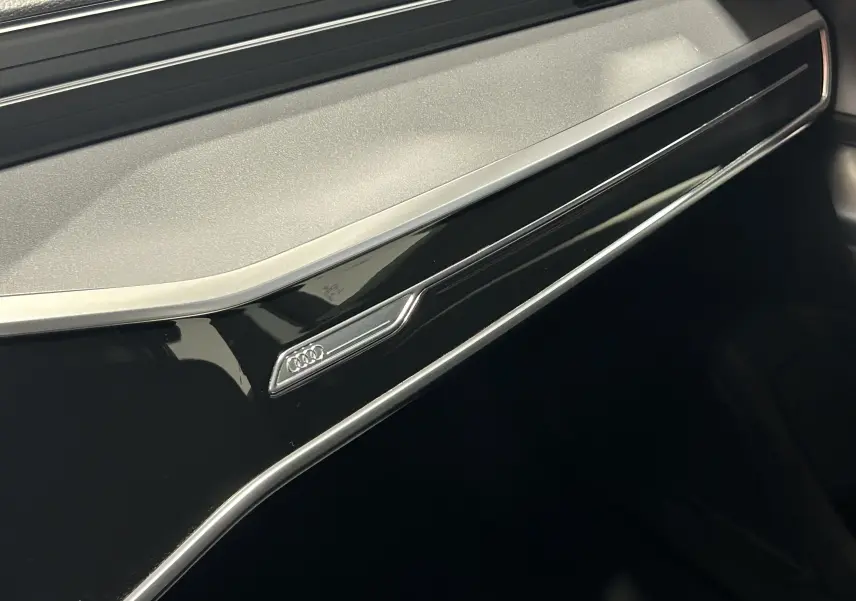 Détail intérieur du tableau de bord noir brillant de l'Audi A6 Avant 40 TDI 2019 avec logo Audi chromé.