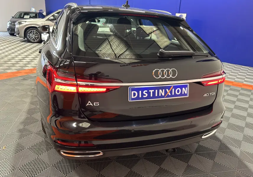 Vue arrière d'une Audi A6 Avant noire de 2019 avec feux LED allumés dans un showroom au sol damier.