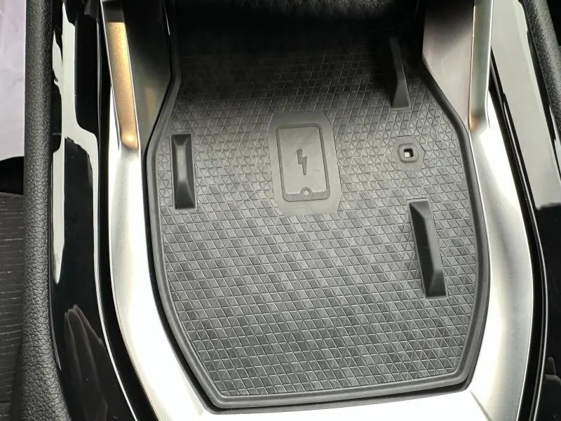 Gros plan sur le chargeur à induction noir intégré à la console centrale du Renault Austral Rouge Flamme 2025.