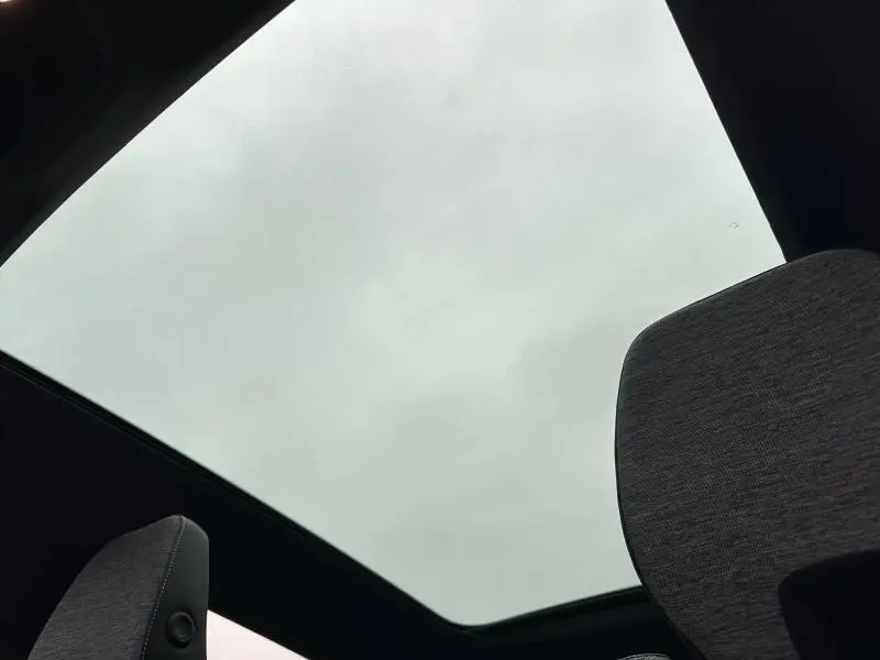 Vue intérieure du toit ouvrant panoramique du Renault Austral 2025, avec appuie-tête en tissu gris visible au premier plan.