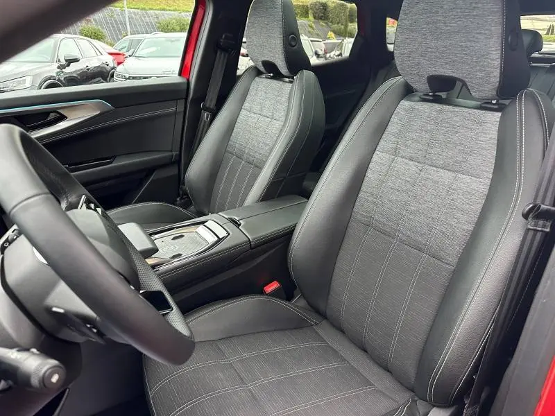 Vue intérieure côté conducteur du Renault Austral 2025 rouge flamme, sièges tissu gris avec surpiqûres blanches et console centrale moderne.