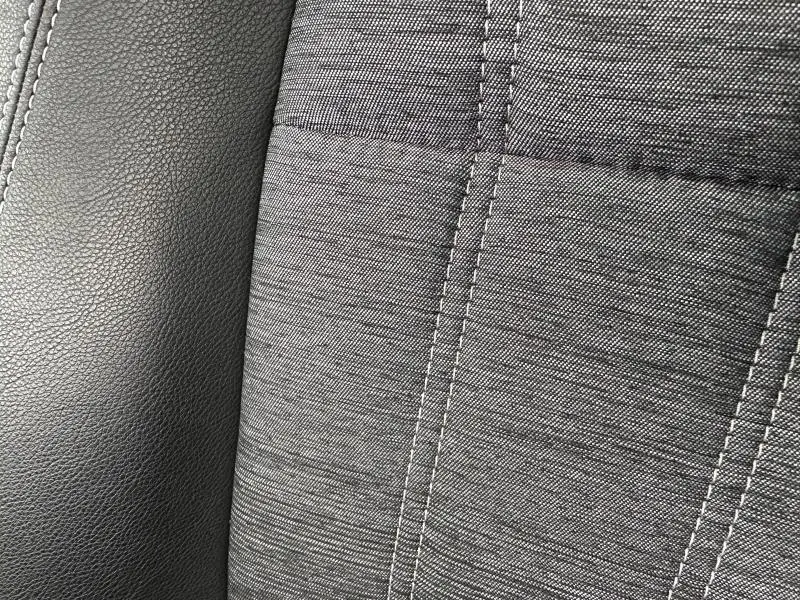 Détail du revêtement de siège en tissu gris et cuir noir du Renault Austral 2025, version hybride Rouge Flamme.