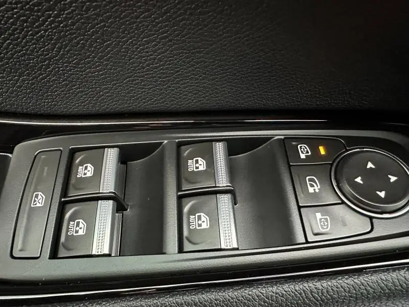 Gros plan sur les commandes des vitres électriques et rétroviseurs d’un Renault Austral 2025, intérieur noir.