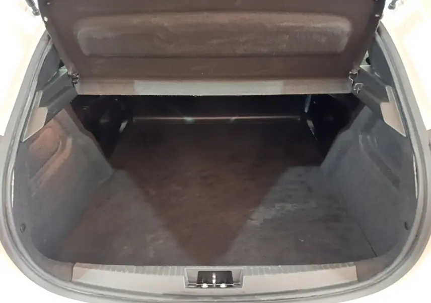 Coffre ouvert vu de l'arrière d'une Peugeot 208 blanche, montrant un espace de chargement vide et propre.