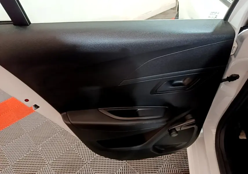 Vue rapprochée de la porte arrière droite noire d'une Peugeot 208 blanche de 2022, avec poignée intérieure visible.