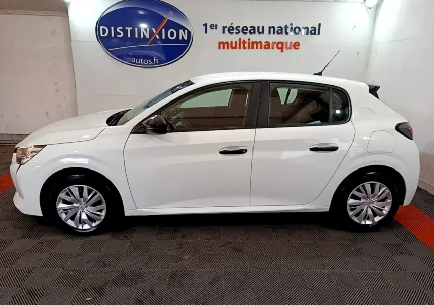 Vue latérale droite d'une Peugeot 208 blanche de 2022, compacte et moderne, stationnée en intérieur sur sol carrelé.