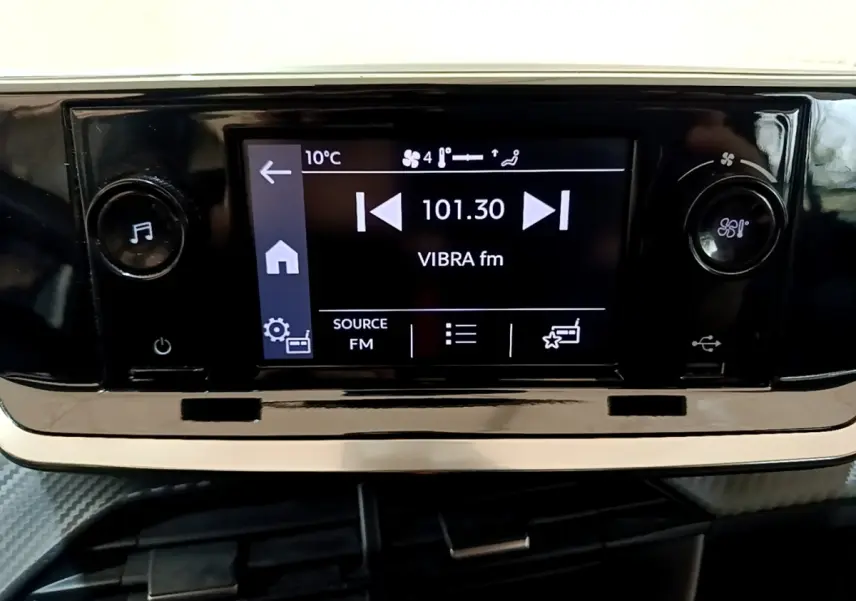 Écran tactile central de la Peugeot 208 blanc montrant la radio FM à 101.30 MHz avec commandes de volume et ventilation.