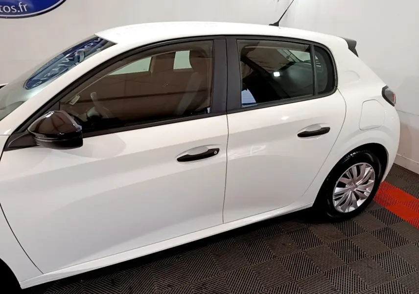 Vue latérale côté gauche d'une Peugeot 208 blanche, mettant en valeur les poignées de porte et les jantes en alliage.
