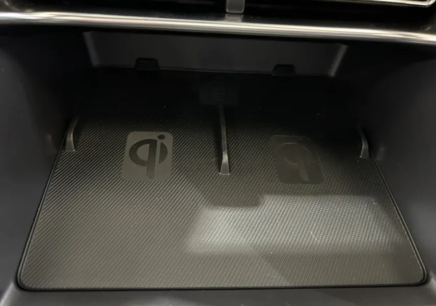 Gros plan sur la zone de recharge sans fil Qi dans l'habitacle du BYD SEAL U, surface noire texturée.