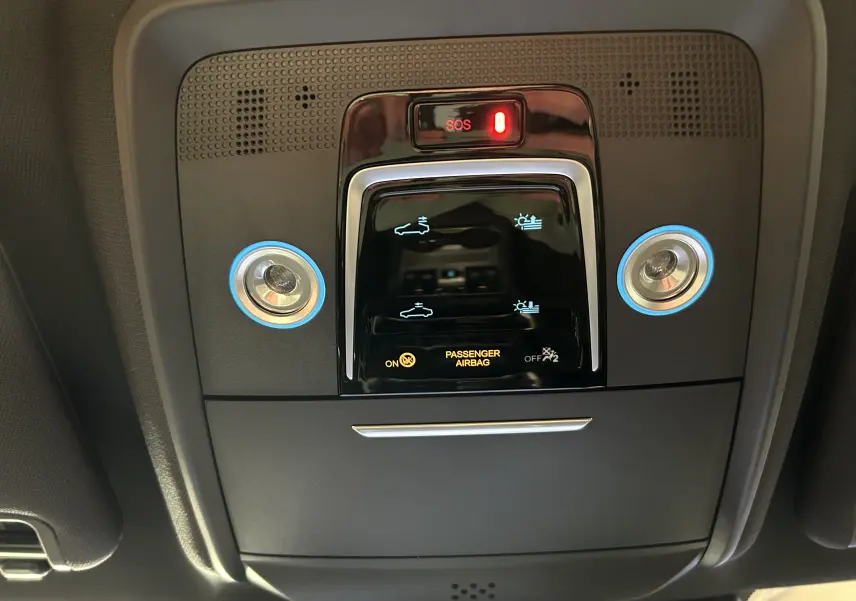 Vue en plongée du panneau de commande intérieur noir brillant du toit ouvrant du BYD SEAL U avec éclairage bleu autour des boutons.