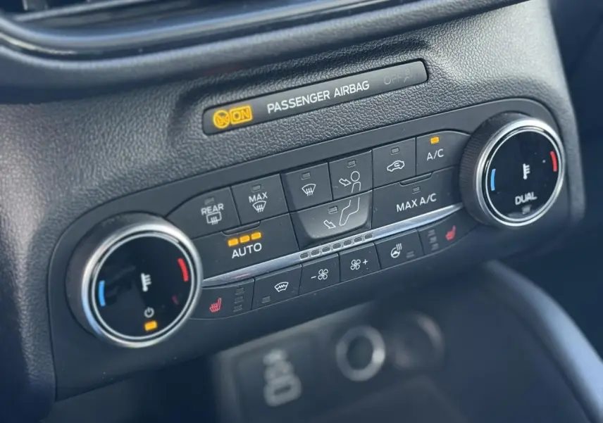 Gros plan sur la console de climatisation automatique bi-zone avec commandes chauffantes du Ford Kuga 2024 rouge Lucifer.