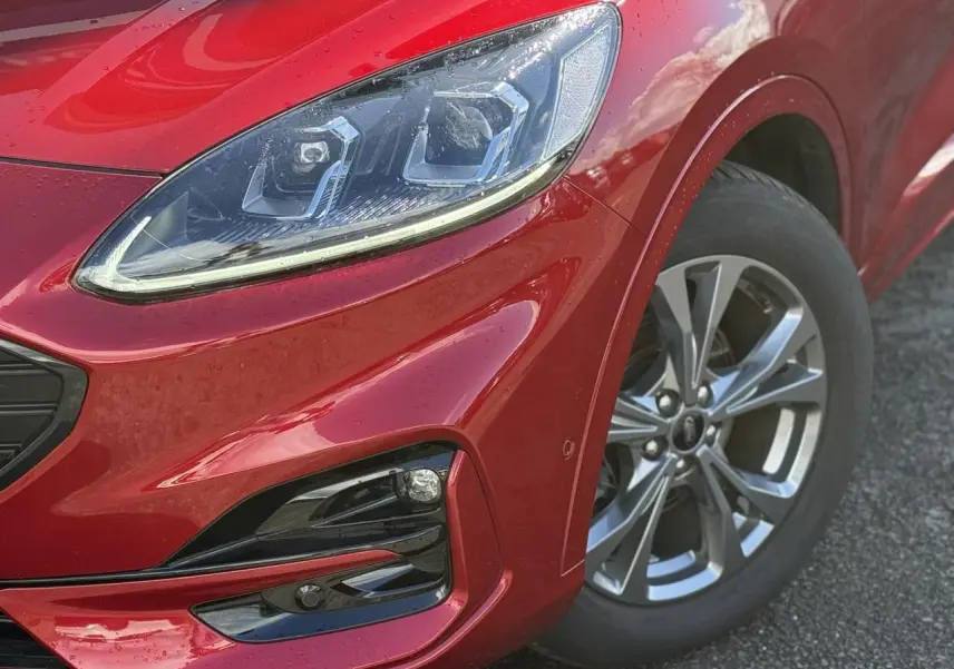 Gros plan sur l'avant droit rouge Lucifer du Ford Kuga 2024, mettant en valeur le phare LED et la jante alliage 18 pouces.