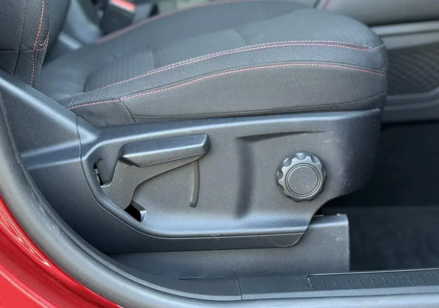 Gros plan sur le côté gauche du siège avant noir avec surpiqûres rouges du Ford Kuga Rouge Lucifer 2024.