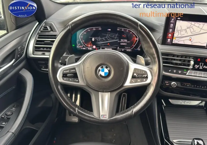 Vue intérieure centrée sur le volant cuir noir multifonction du BMW X4 (g02) xdrive30d 2022 avec tableau de bord digital et écran tactile.