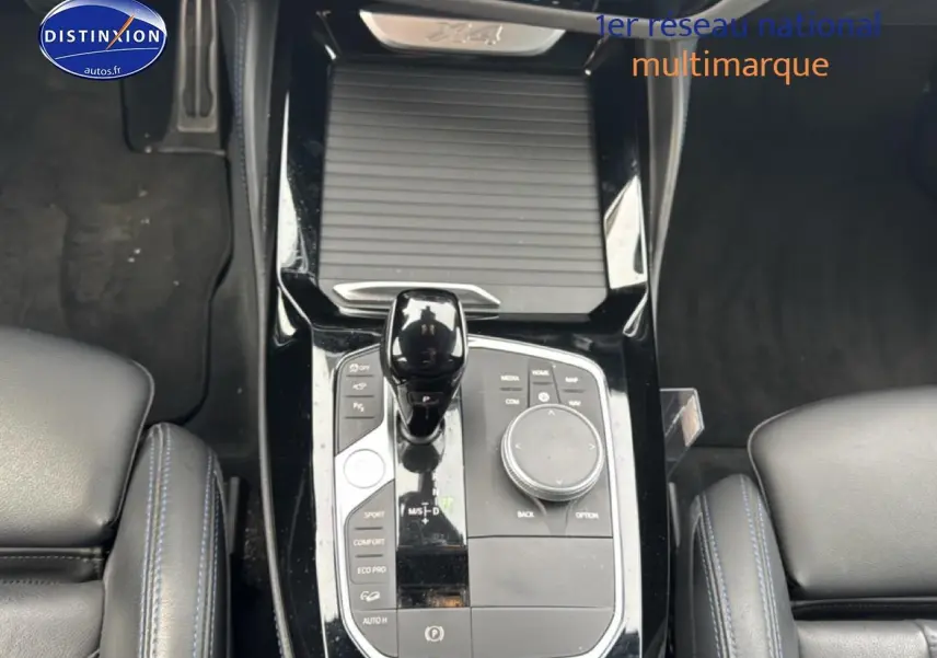 Vue plongeante sur la console centrale noire du BMW X4 xDrive30d 2022 avec levier de vitesse et commandes multifonctions.