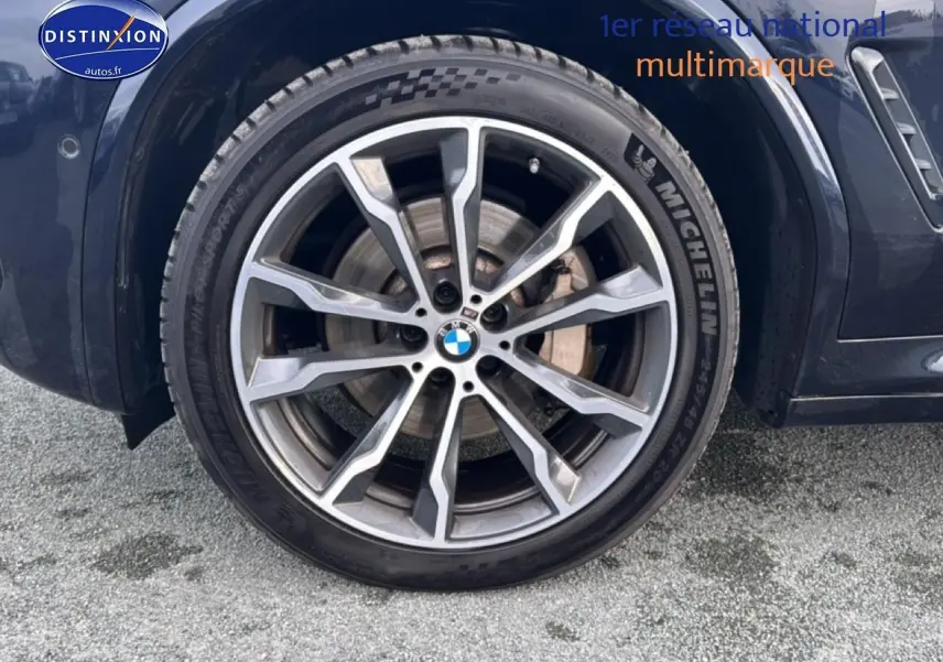 Gros plan sur la roue avant droite avec jante alu et logo BMW sur BMW X4 noir (g02) xdrive30d 2022.
