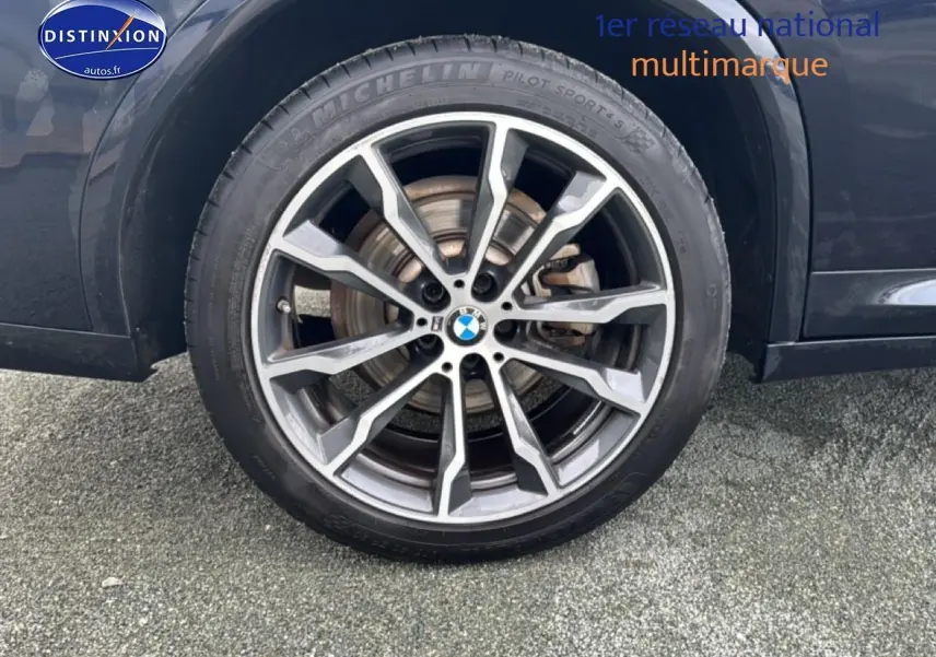 Gros plan sur la jante alu grise et le pneu Michelin du côté arrière droit d’un BMW X4 noir.