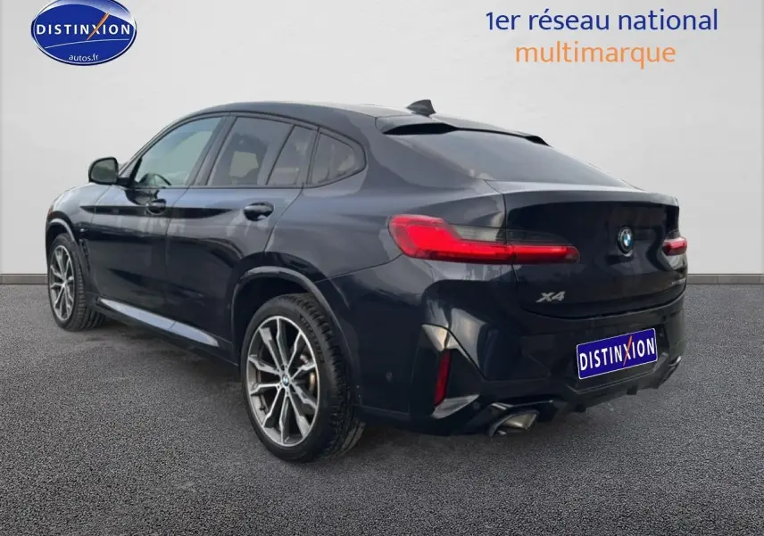 BMW X4 noir vue 3/4 arrière droit, avec feux arrière LED et double sortie d’échappement chromée.