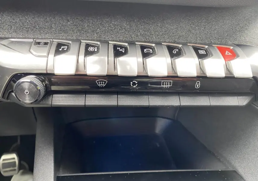 Gros plan sur la rangée de commandes centrales argentées et noires du tableau de bord du Peugeot 3008 blanc, version GT Line.