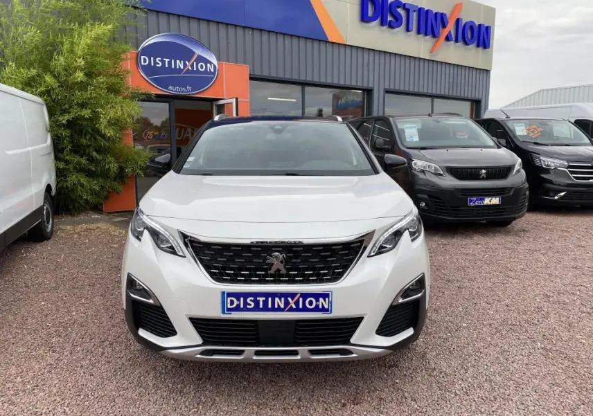 Vue frontale d’un Peugeot 3008 blanc GT Line 2018, avec calandre noire et logo lion distinctif, devant un concessionnaire.