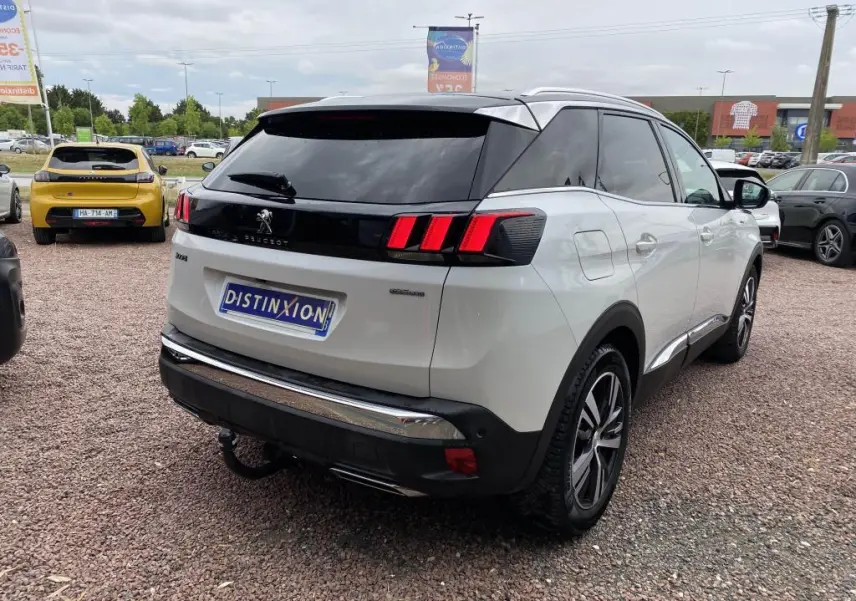 Peugeot 3008 blanc vue 3/4 arrière droit, feux arrière à triple griffes rouges et toit noir contrasté.