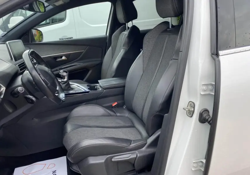 Vue intérieure côté conducteur du Peugeot 3008 blanc 2018, sièges en cuir et tissu, volant et levier de vitesse manuelle visibles.