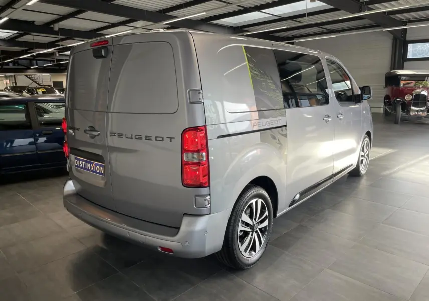 Peugeot Expert Fourgon gris Artense vu 3/4 arrière droit en intérieur avec jantes alliage et décor latéral noir et vert.