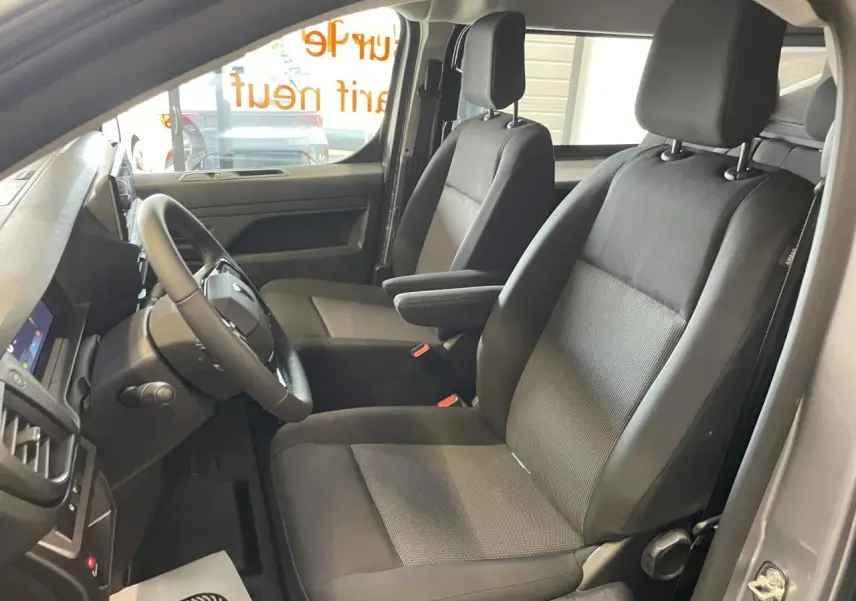 Vue intérieure côté conducteur du Peugeot Expert Fourgon gris Artense, montrant les sièges avant et le volant.