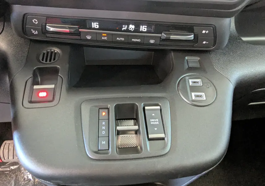 Vue rapprochée de la console centrale noire du Citroën Berlingo 2026, avec commandes de climatisation et sélection de mode de conduite.