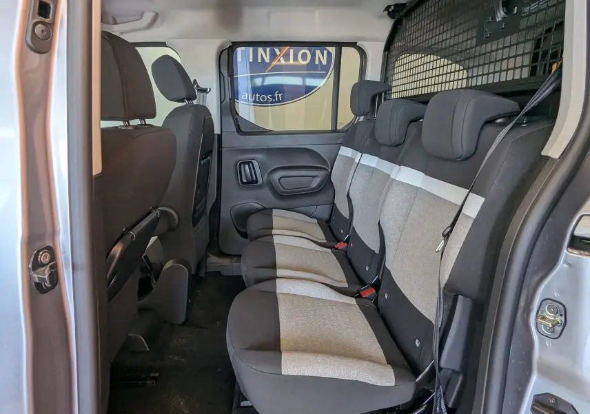 Vue latérale intérieure côté droit du Citroën Berlingo gris Artense, montrant la banquette arrière trois places en tissu bicolore.