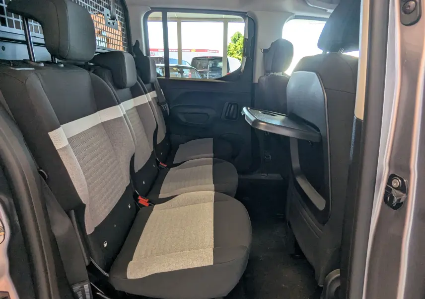 Vue intérieure côté droit des sièges arrière en tissu gris clair et noir du Citroën Berlingo gris Artense 2026 avec tablette rabattable.