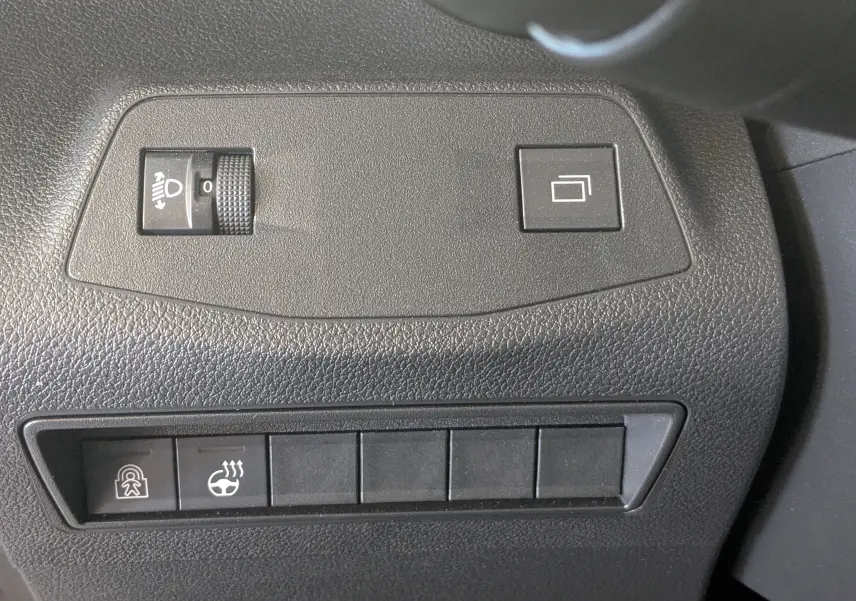 Gros plan sur les commandes de réglage des phares et du volant chauffant dans un Citroën Berlingo gris Artense, intérieur noir.