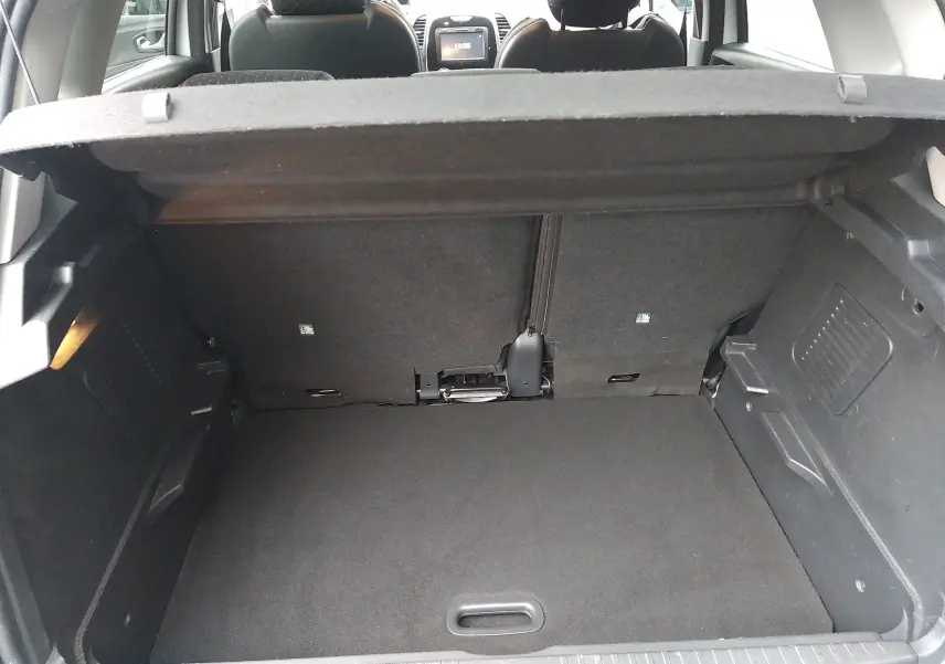 Coffre ouvert d’un Renault Captur blanc, vue depuis l’arrière montrant l’espace de chargement et les sièges arrière.