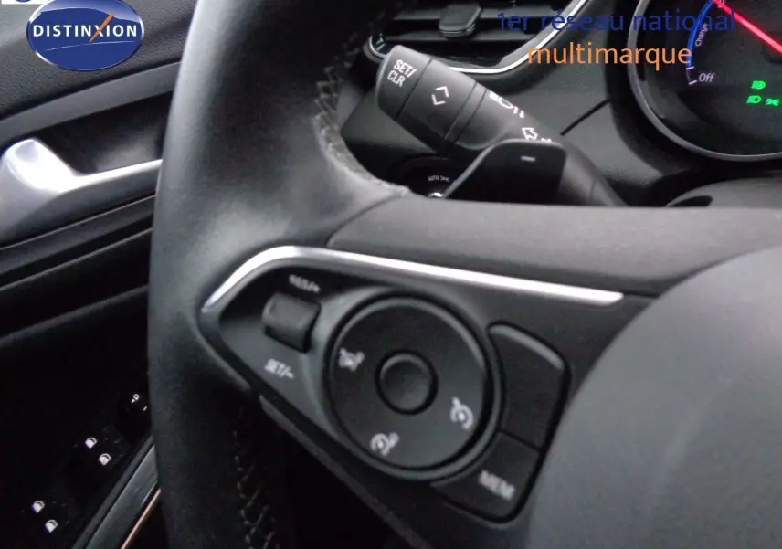 Gros plan sur le volant noir de l'Opel Grandland X 1.6 Hybrid Turbo 2021, montrant les commandes intégrées côté gauche.