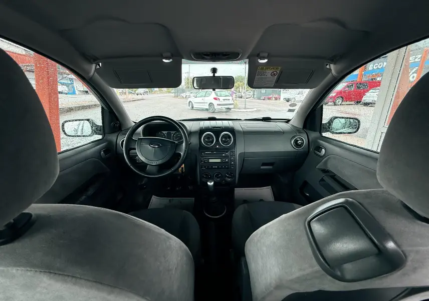 Vue intérieure avant de la Ford Fusion 2002 avec tableau de bord noir et sièges tissu gris clair.