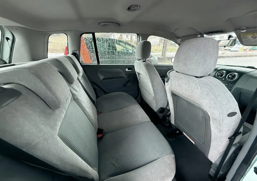 Vue intérieure arrière montrant les sièges gris clair de la Ford Fusion 2002 avec une porte arrière ouverte côté droit.