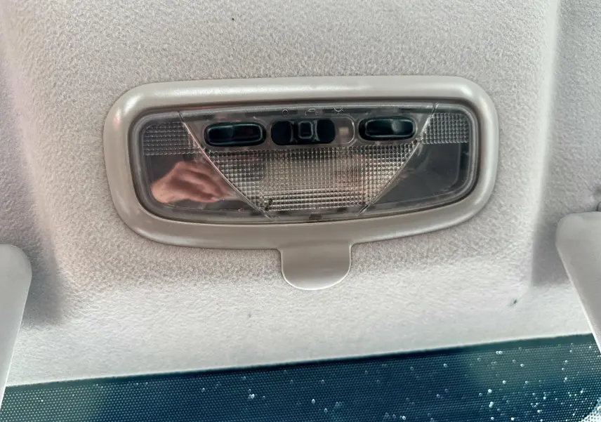 Plafonnier intérieur gris clair de la Ford Fusion 2002 visible au-dessus du pare-brise avec boutons de commande intégrés.