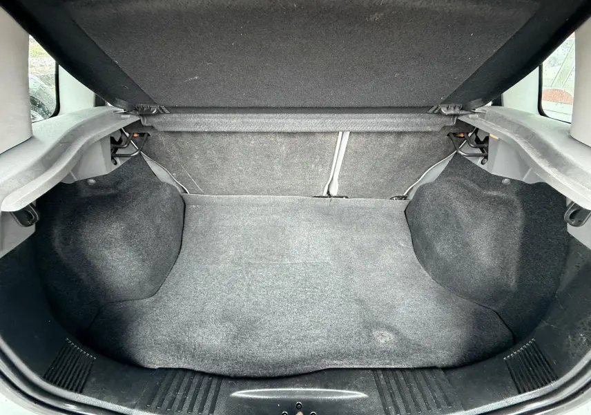 Coffre ouvert de la Ford Fusion 2002, vue intérieure montrant le revêtement gris et l'espace de rangement vide.