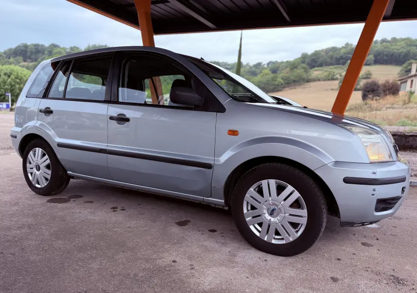 Ford Fusion bleu clair vue de profil côté gauche sous un abri avec arrière-plan rural.