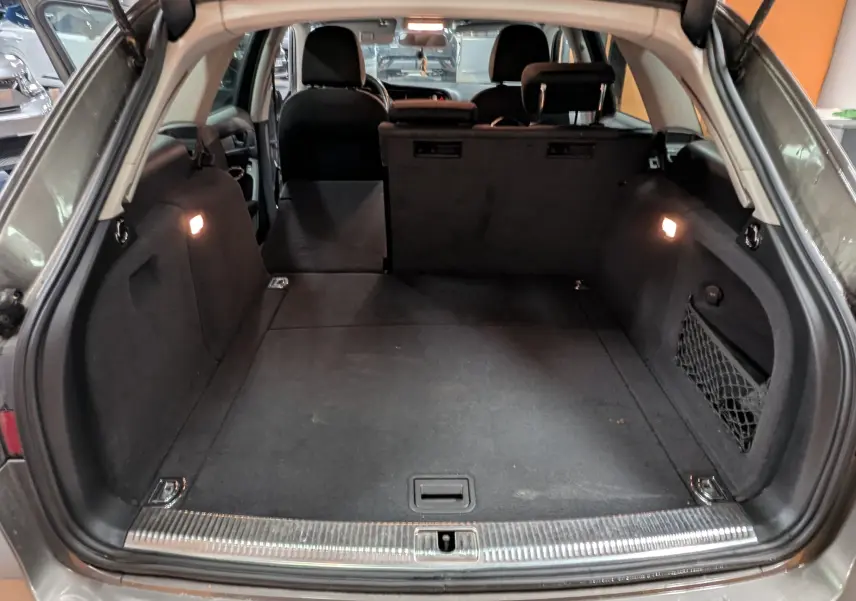 Coffre ouvert d'une Audi A4 gris 2013, vue arrière montrant l'espace de chargement et les sièges rabattus.