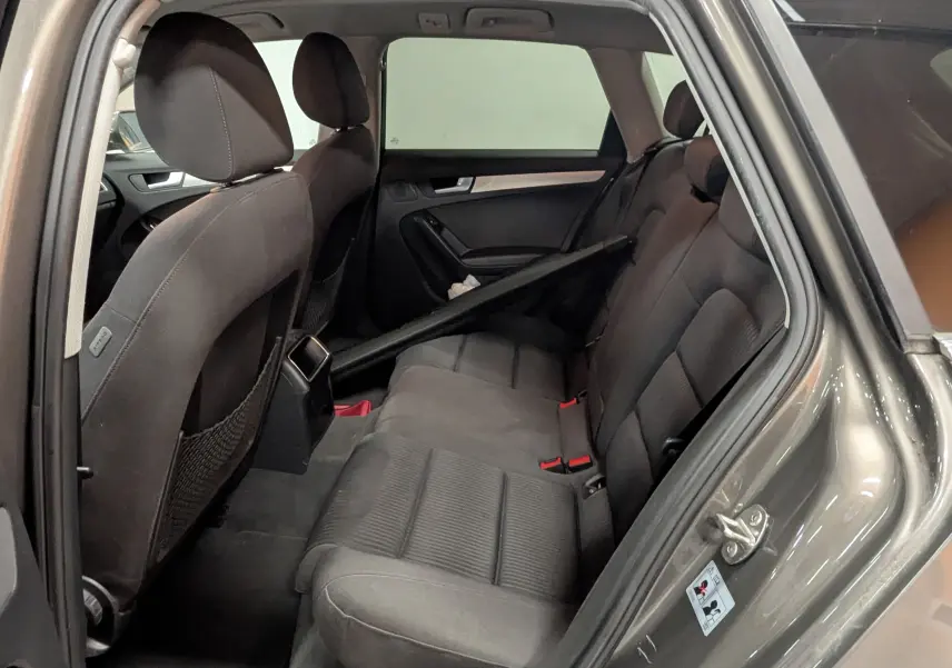 Vue intérieure côté droit sur les sièges arrière en tissu noir d'une Audi A4 gris 2013 avec porte ouverte.